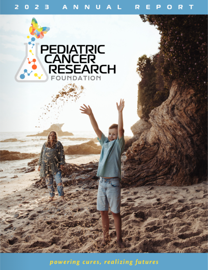 Adult and child play in the sand of an ocean beach, with a bright sky on a clear day.