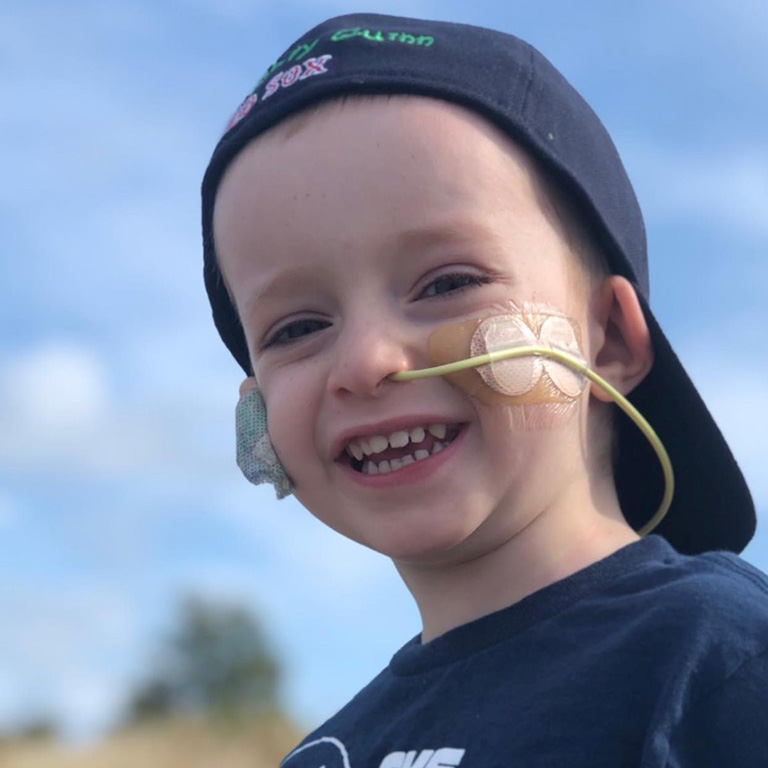 a boy smiling in a red sox hat