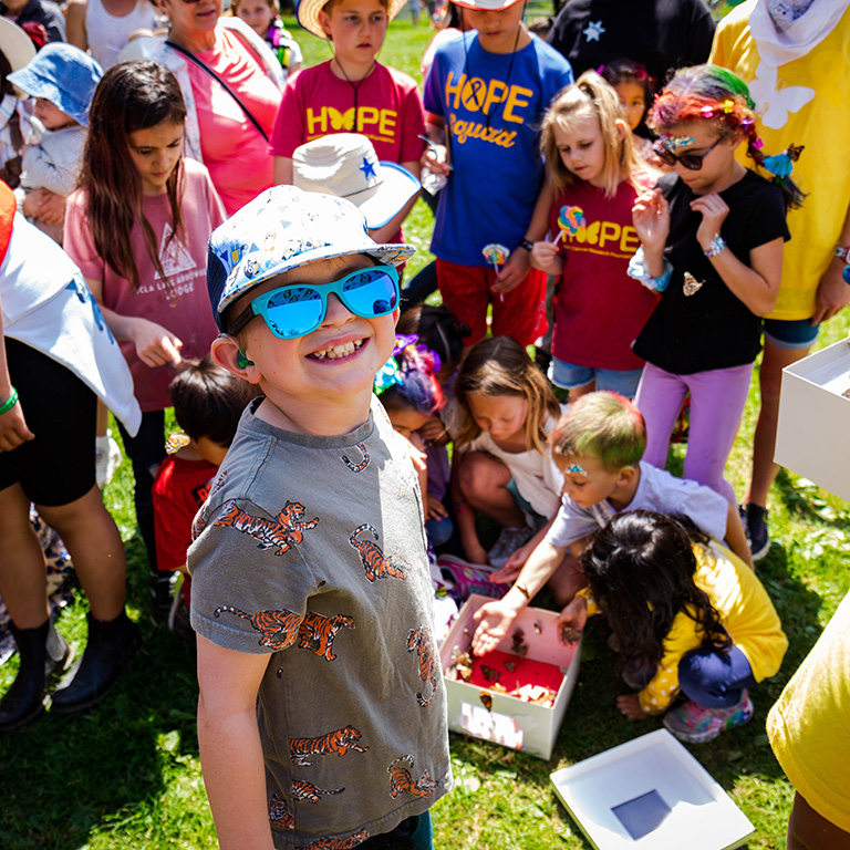 a child in sunglasses and a hat smiling at party