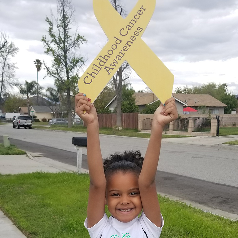 a child holding up a childhood cancer awareness sign