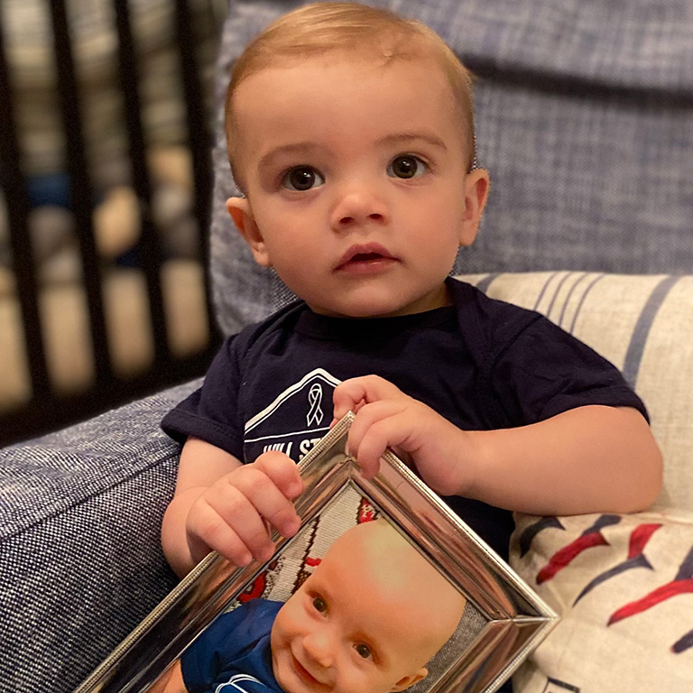 a child holding a portrait of his baby brother