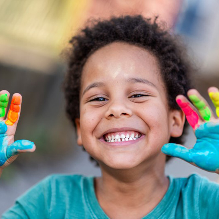 A child smiling with paint on their hands