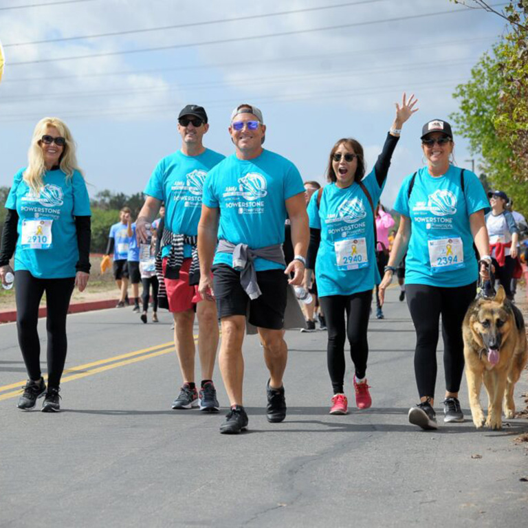 A group of marathon walkers wearing matching blue shirts.