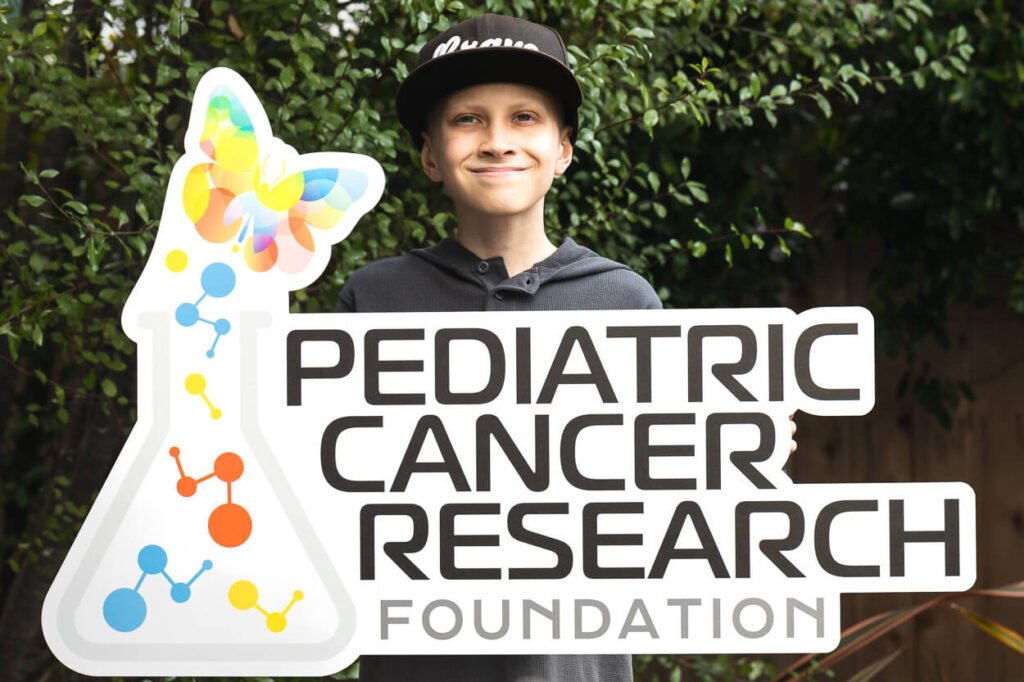 A child holding a Pediatric Cancer Research Foundation Sign