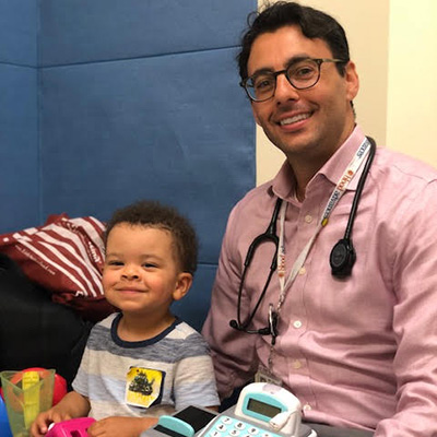 Dr Stieglitz sitting next to a young child patient.