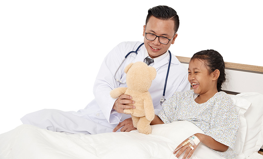 Doctor handing a teddy bear to a patient in a hospital bed.