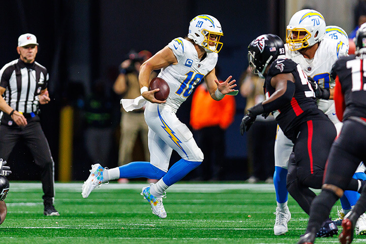 Chargers QB Justin Herbert scrambling out of the pocket on a football play in the NFL